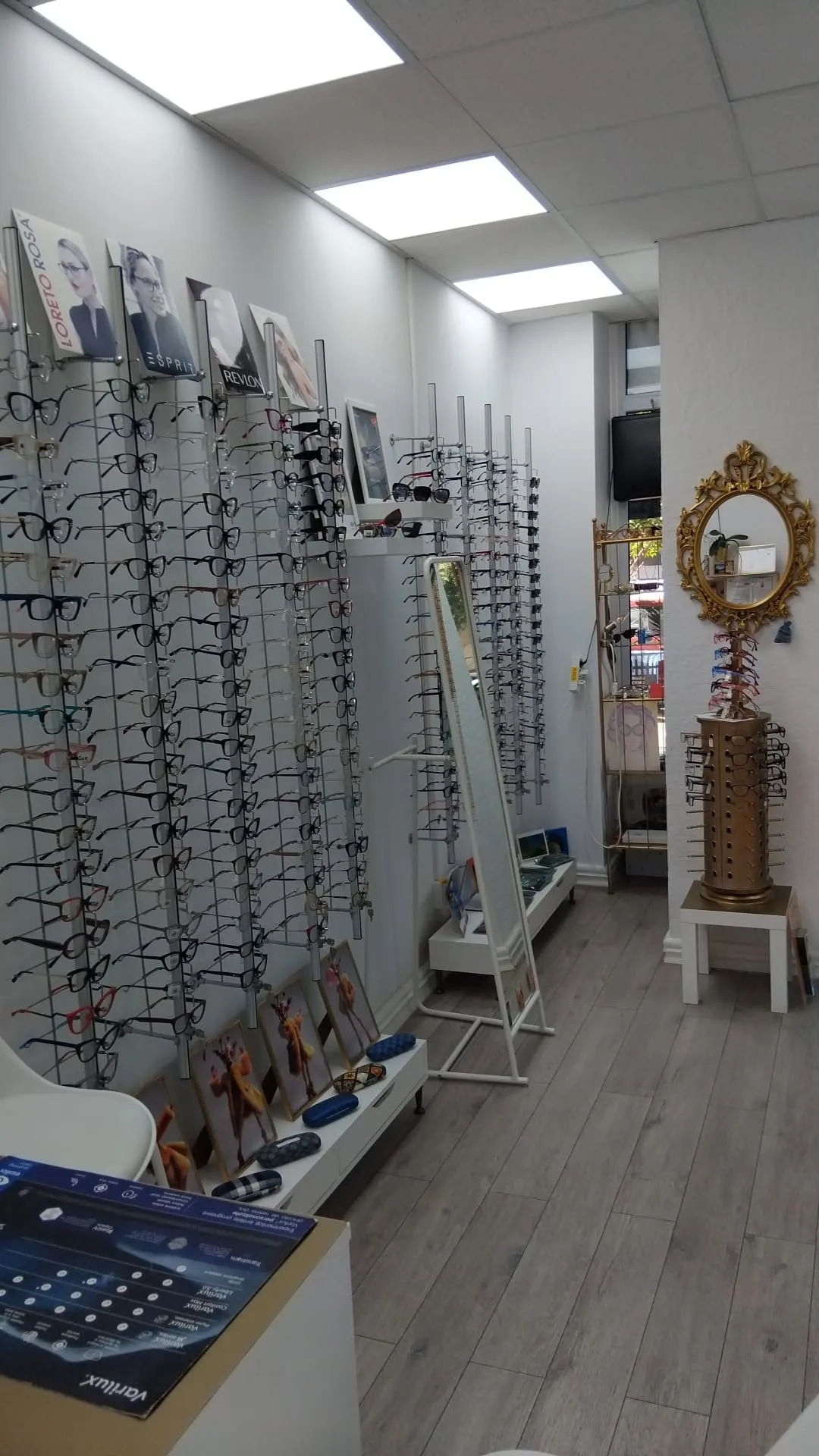 Peretele cu rame de ochelari și oglinda aurie din magazinul L’optique Monique de pe Bd. Chișinău