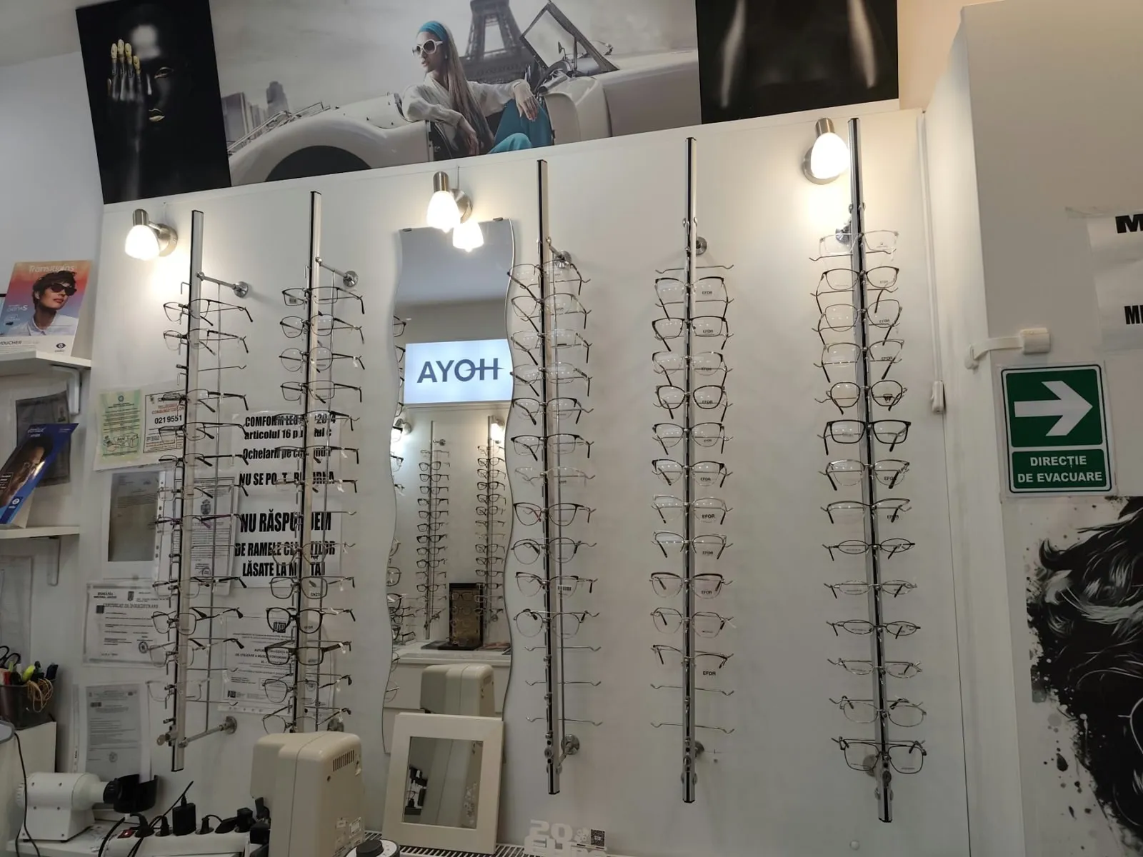 Rame de ochelari expuse lângă oglinda din magazinul L’optique Monique de la Obor
